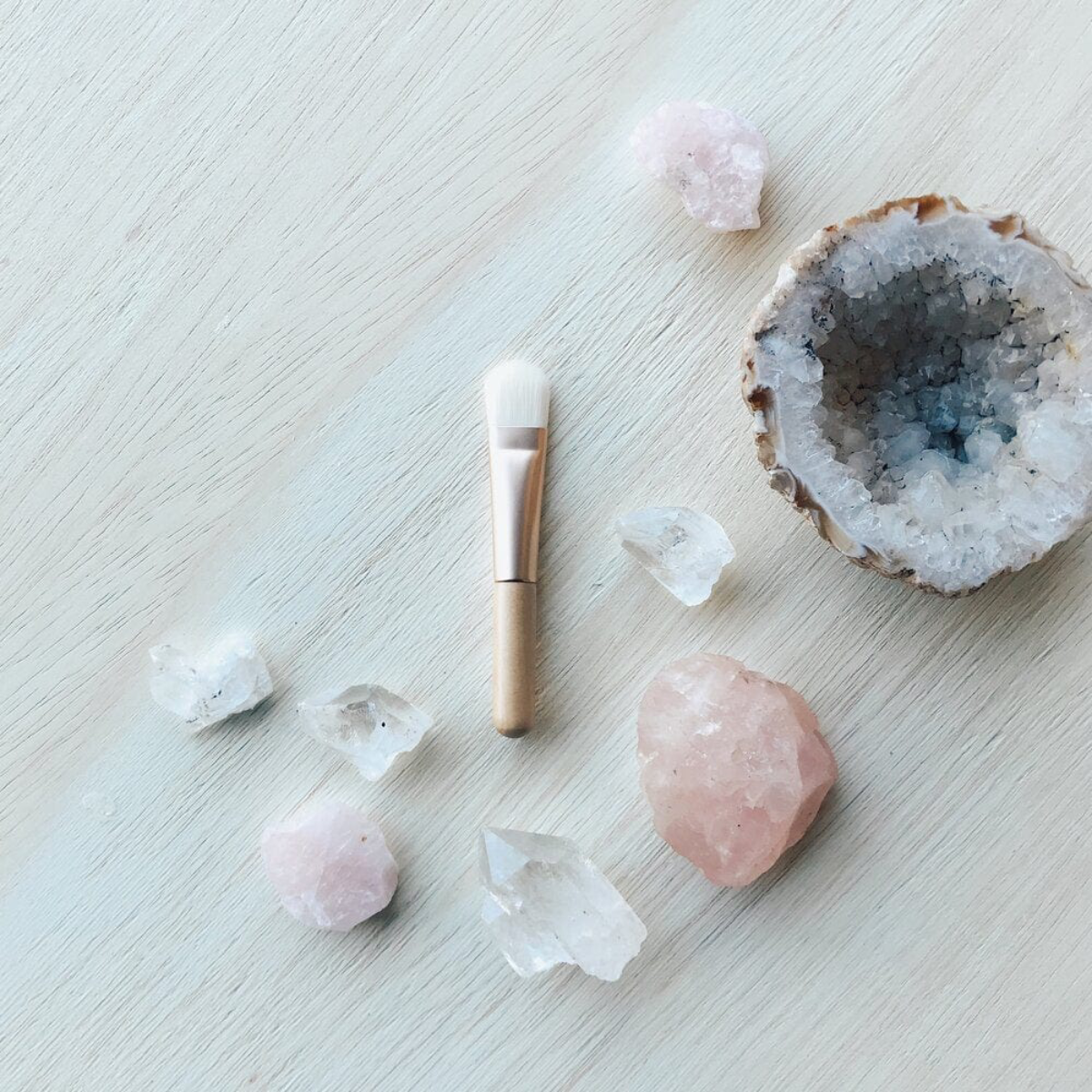 Crystal geode, rose quartz, clear crystal points on a light wooden surface