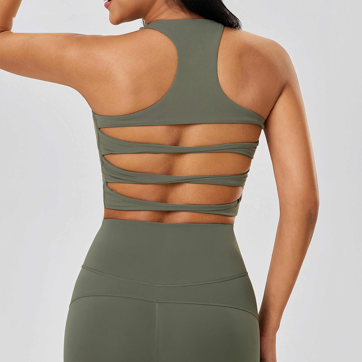 Person wearing a green sports bra and leggings set on a light gray background